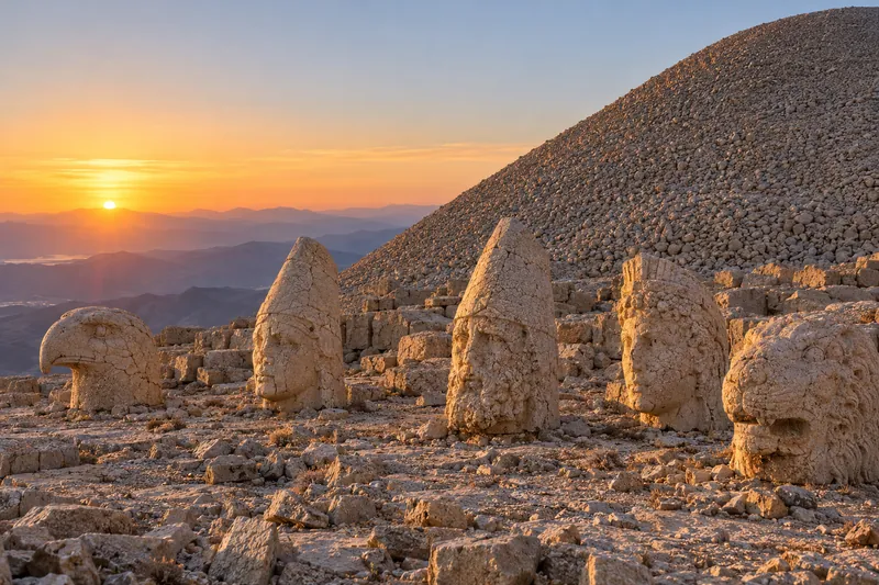 Colossal stone heads of gods, an eagle and a lion before the summit tumulus of Mount Nemrut at sunrise