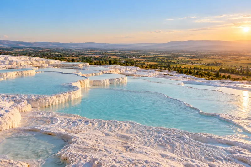 White travertine terraces and turquoise pools of Pamukkale at sunset