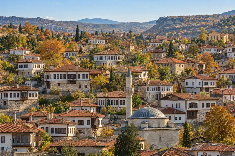 Whitewashed Ottoman timber houses and a domed mosque on the hillsides of Safranbolu in autumn