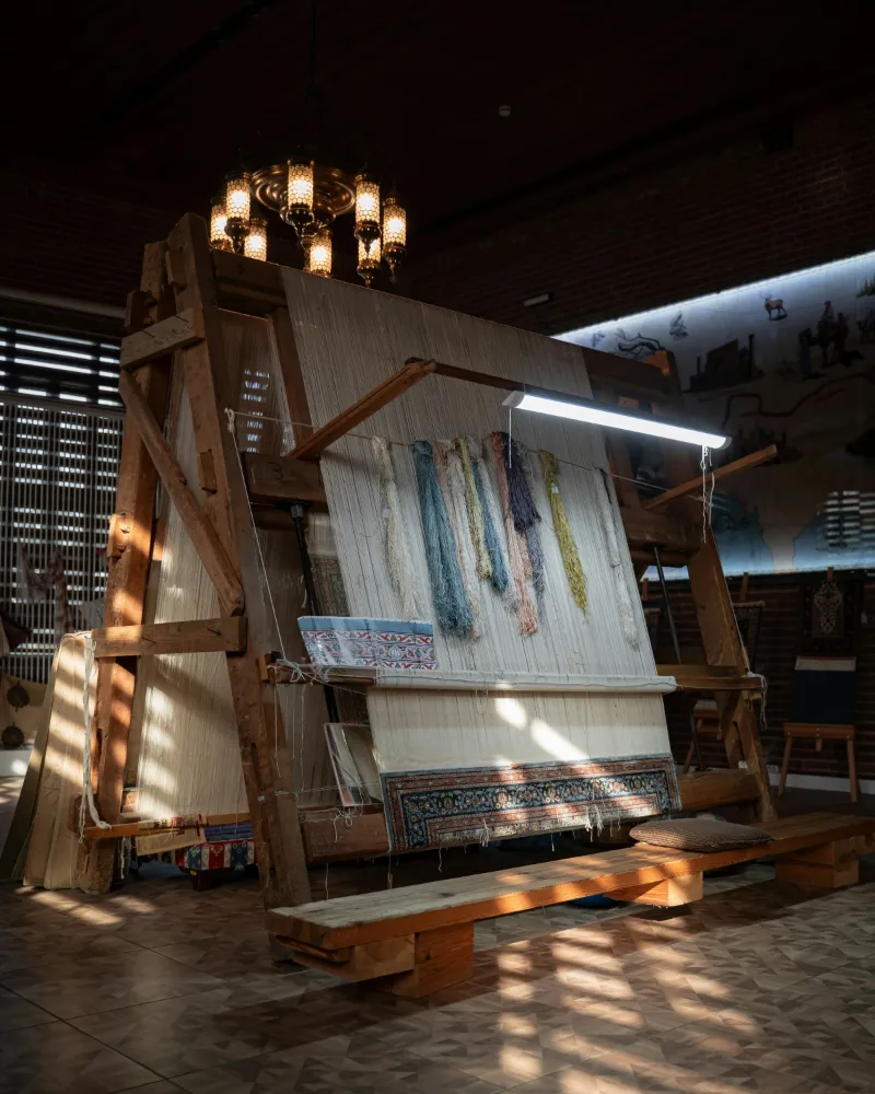 A wooden hand loom with a half-woven rug in a weaving workshop in Bursa