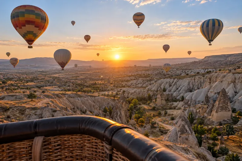 View from a hot air balloon basket at sunrise over the valleys of Cappadocia, other balloons around