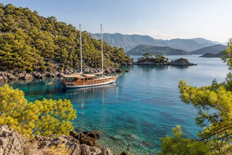 A wooden gulet anchored in a turquoise, pine-fringed bay of the 12 Islands near Fethiye