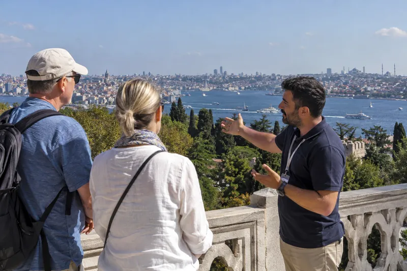 A licensed guide on a Topkapi Palace terrace pointing out the Golden Horn and Galata to a couple