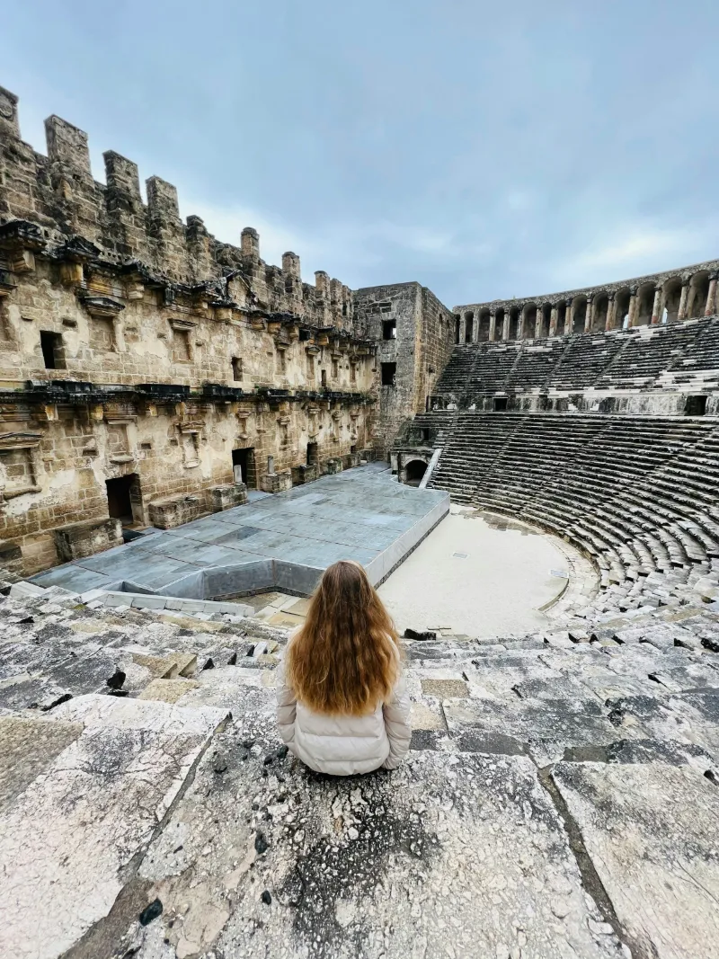 A traveler on the upper seats of the Roman theater of Aspendos, looking down at the stage building