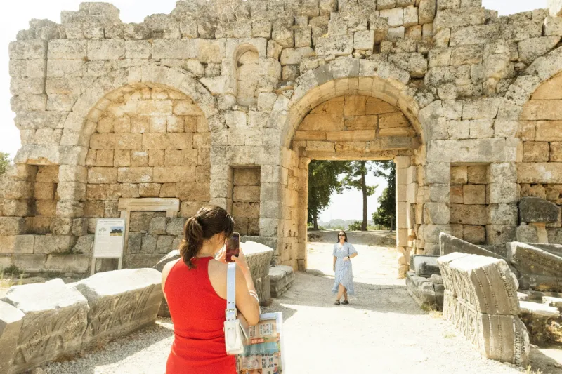 A traveler photographing a Roman arched gateway in the ancient city of Perge near Antalya
