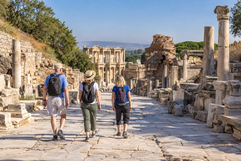 Travelers walking down the marble Curetes Street toward the Library of Celsus in Ephesus in the morning