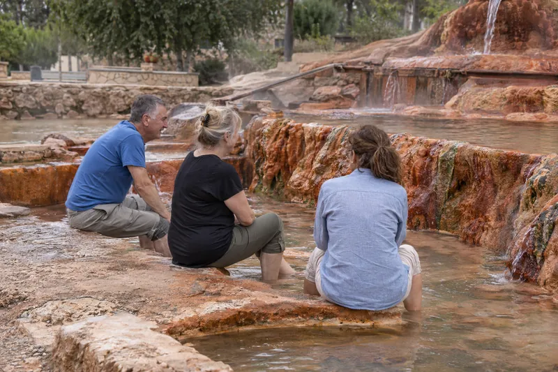 Travelers soaking their feet in the red thermal pools of Karahayit near Pamukkale