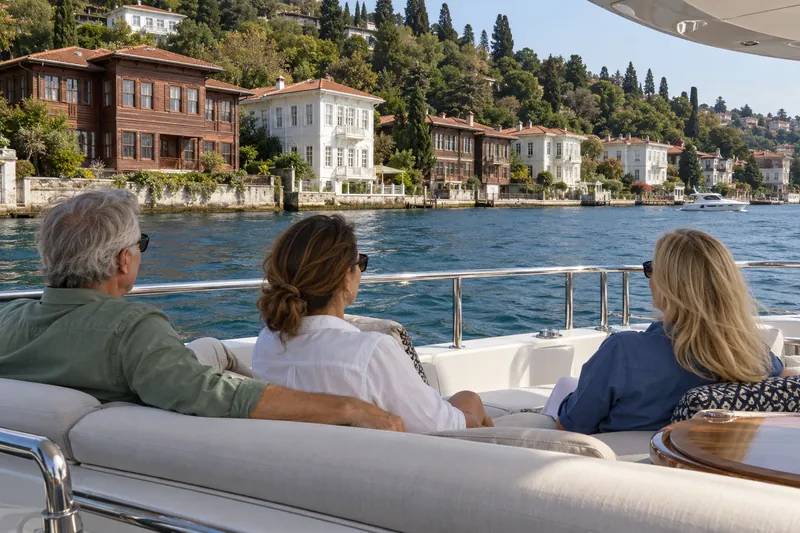 Travelers on a private yacht passing the wooden waterfront mansions (yali) of the Bosphorus