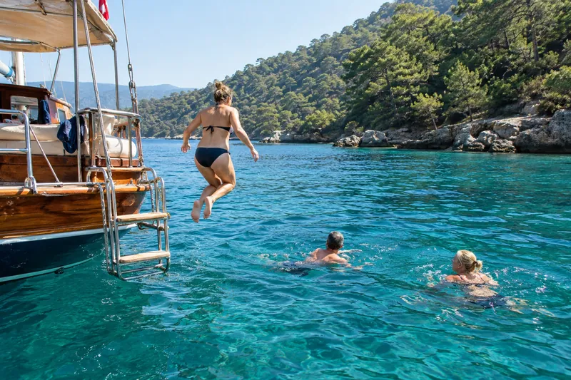 Travelers jumping and swimming from a private boat in a turquoise cove near Fethiye