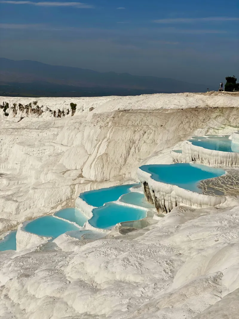Visitors on the white travertine terraces of Pamukkale above turquoise thermal pools